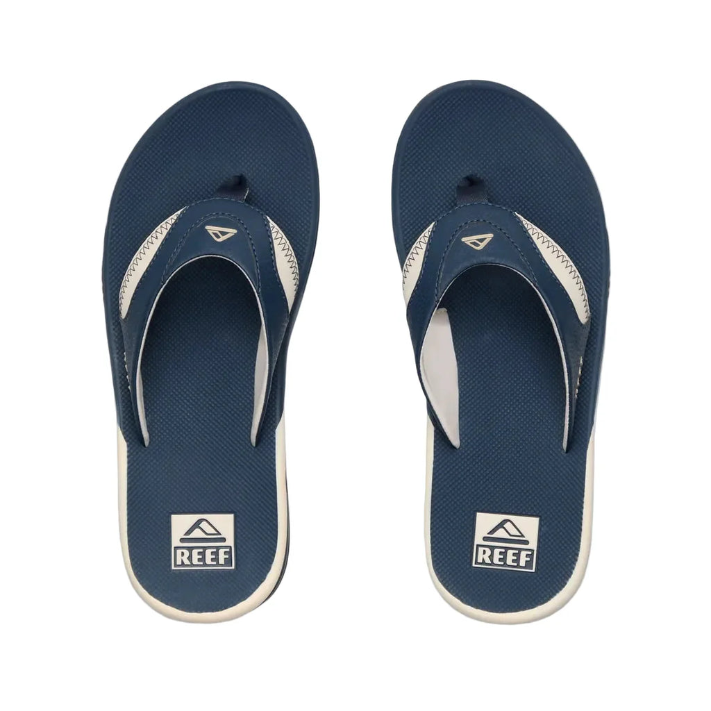 Pair of navy blue and white Reef sandals on a white background