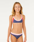 Young girl wearing a colorful bikini against a white background