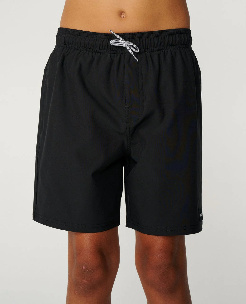 Black Ripcurl shorts worn by a boy on a plain background