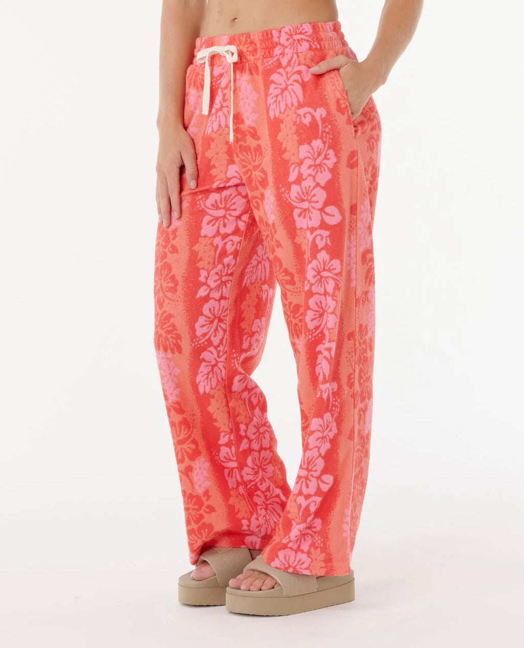 Person wearing coral floral pants on a white background