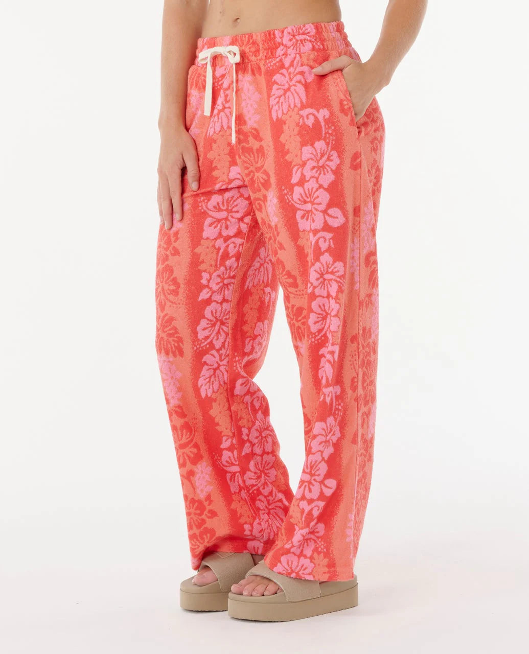 Person wearing coral floral pants on a white background